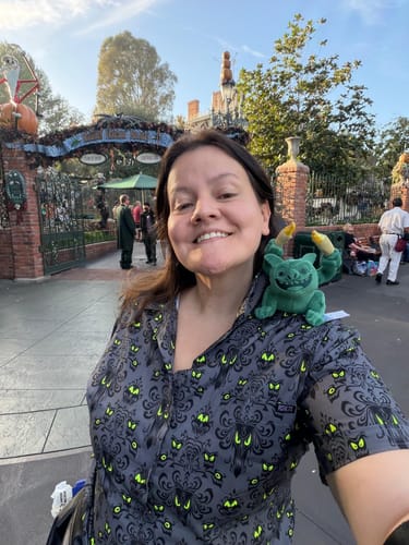 Customer wearing the Disney's Haunted Mansion “Wall Creeps” shirt, smiling for a selfie in front of the attraction.