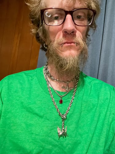 Reviewer wearing the large FALLEN ANGEL PENDANT on a thick chain, layered with other necklaces.
