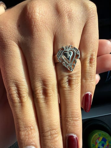 Customer's hand wearing a silver heart-shaped ring with a custom initial engraved on it.