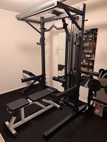 Kundenfoto des schwarzen R7 Rider Squat Racks, aufgebaut in einem Heim-Fitnessstudio mit Hantelbank und Latzug.