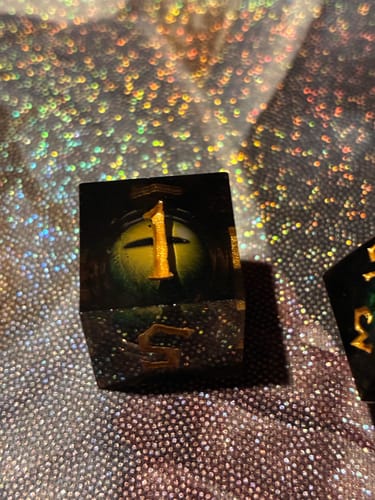 Close-up of a customer's sharp-edged Jurassic Yellow Liquid Core die, showing the yellow eyeball and the number one.