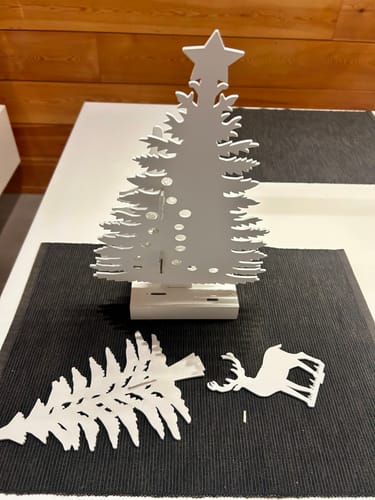 Klant toont de witte LED-decoratie die gebroken op tafel ligt met de losse, afgebroken stukken ernaast.