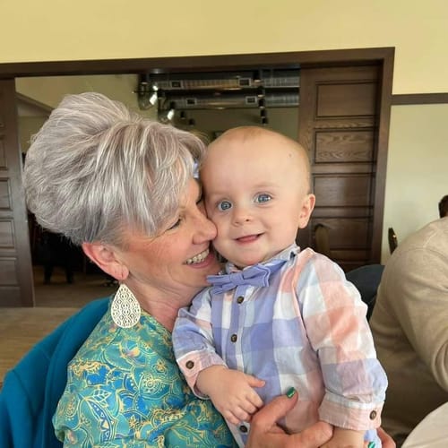 Reviewer's lifestyle photo, showing them smiling happily while holding a baby.
