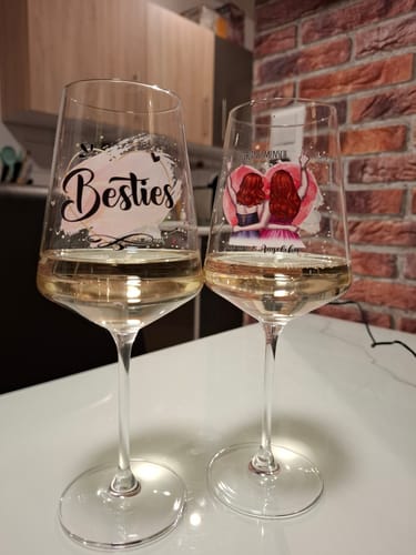 Kundenfoto von zwei personalisierten Leonardo Puccini Weingläsern mit Weißwein auf einem Tisch.