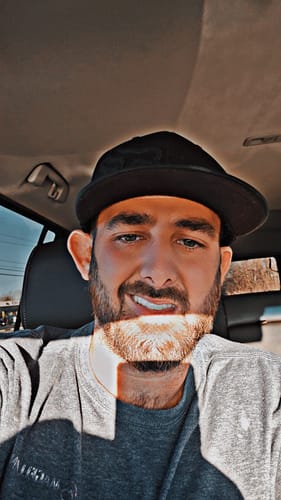 Customer sitting in a car showing a bright, confident smile with his Pop On Veneers.