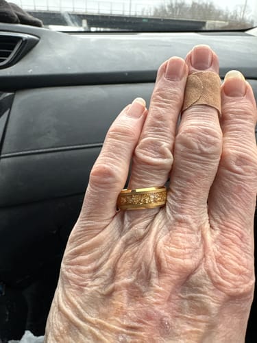 Customer's hand wearing the gold Aureum ring with a textured foil inlay while in a car.