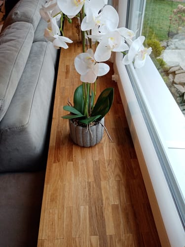 Rezensent zeigt eine mit Easy-Sticks kreativ verkleidete Fensterbank, auf der eine weiße Orchidee steht.
