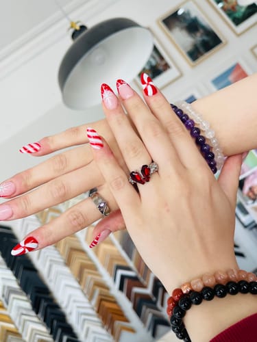 Customer's hand with festive nails, showing the red coffin-shaped Promise Ring on their finger.
