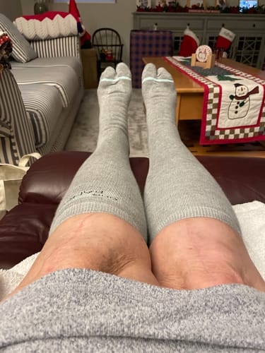Customer relaxing with feet up, wearing grey, split-toe Premium Bamboo Compression Socks.
