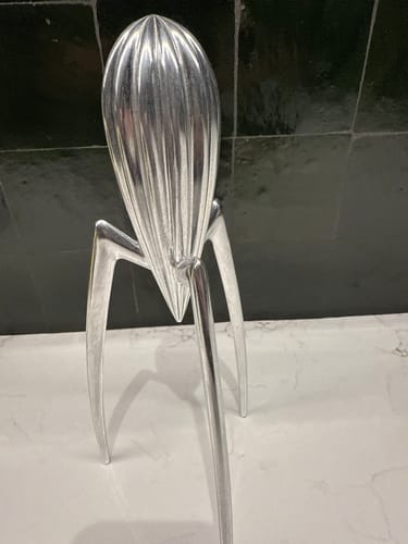 Recensent toont de Alessi Juicy Salif citruspers met een matte, doffe afwerking op een aanrecht.