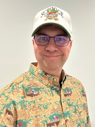 Reviewer wearing the patterned "Counting House Christmas" shirt, featuring Scrooge McDuck among gold coins.
