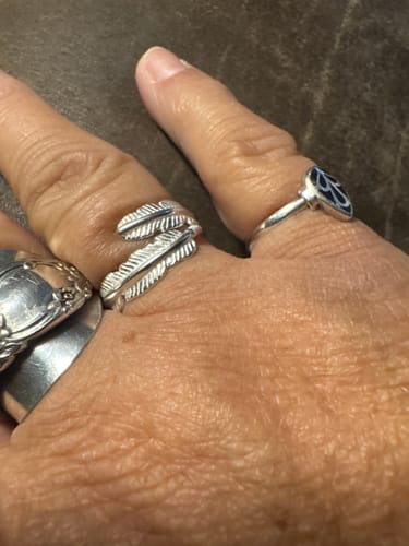 A customer's hand wearing the silver Feather From An Angel Ring, which wraps around their index finger.
