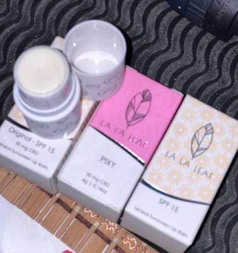 Reviewer's open La La Lips Moisturizing Lip Balm shown with several new product boxes.