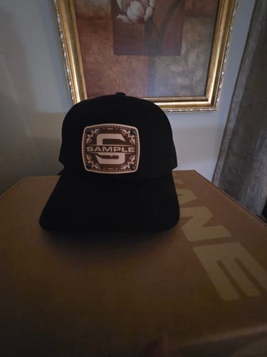 Customer's black Monogram Custom Hat, showing the engraved leather patch with the initial 'S' and 'SAMPLE' text.