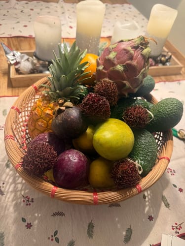 Kunde zeigt Ataulfo Honig-Mangos in einem Korb, arrangiert mit anderen frischen exotischen Früchten.