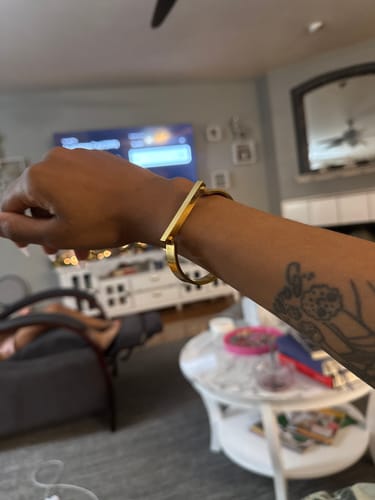 A reviewer's wrist showing the chic, gold Dune Bracelet in a home setting.