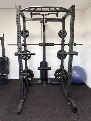 Kunde zeigt das massive R7-Helix Power Rack, komplett aufgebaut in einem Home-Gym auf einem dunklen Boden.