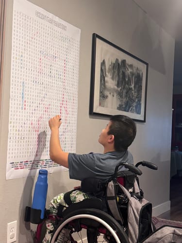 Reviewer in a wheelchair completing the large Christmas Vacation Word Search Puzzle hung on a wall.