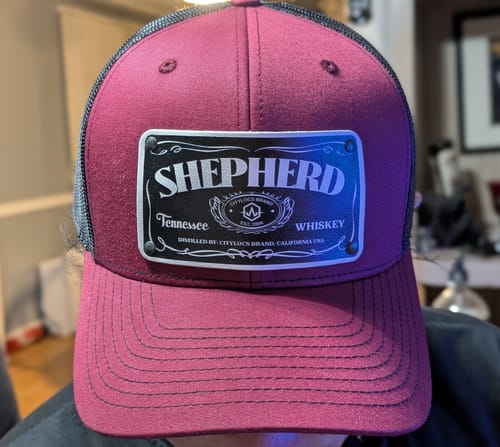A customer's maroon and black Juan Daniels hat featuring a custom leather patch with the name 'SHEPHERD'.