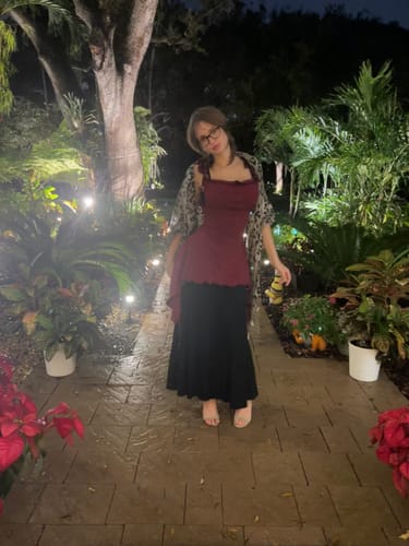 Cliente mostrando el "She Shell" usado como un top arándano y una falda larga negra en el exterior.