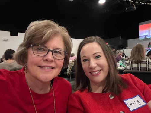 A happy reviewer smiling for a selfie with another person at an event.