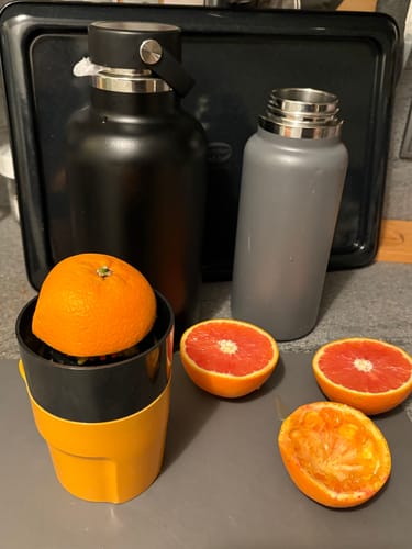 Rezensent presst Saft aus roten Orangen der Weihnachts-Danke Box mit einer Saftpresse.