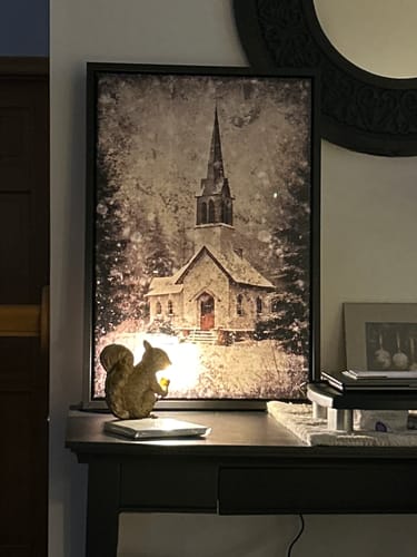 Customer's framed Vintage Church Christmas Wall Art leaning on a dark console table against a wall.