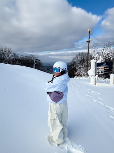 Reviewer in a side profile on a snowy slope wearing the Women's Beige Baggy Snow Pants.