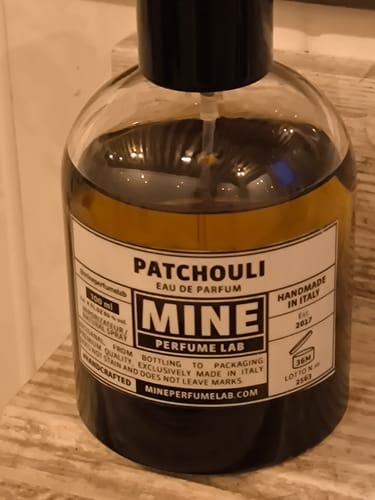 Recensore mostra un primo piano del flacone di vetro dell'eau de parfum Patchouli.