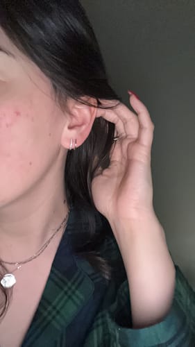 Customer pulls back their hair to show the Silver & Crystal Claw Earrings on their ear.