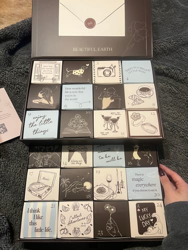 Reviewer showing their open Beautiful Earth Advent Calendar with its two tiers of 24 illustrated gift boxes.
