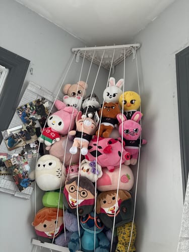 Reviewer's collection of adorable SKZOO plushies shown with other stuffed animals on a hanging corner display.