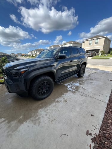 Customer's shiny black SUV parked on a wet driveway after being detailed.