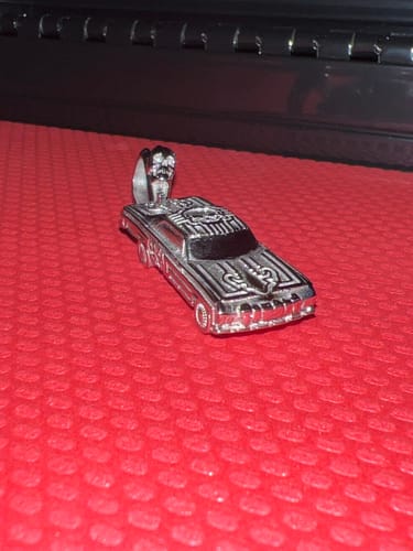 Customer's detailed silver LOWRIDER PENDANT resting on a textured red surface.