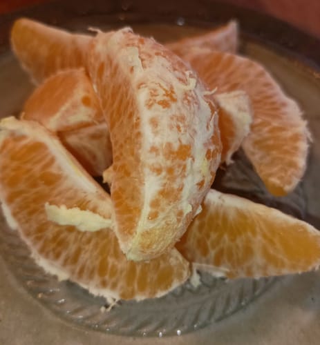 Kunde zeigt die saftigen Bio Navel Orangen in Stücken auf einem Glasteller.