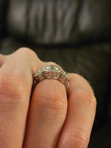 Customer's custom platinum ring on a finger, showing the intricate vintage-style design on the band's side.