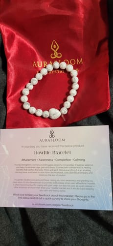 Customer's white beaded howlite bracelet displayed with its branded red pouch and information card.