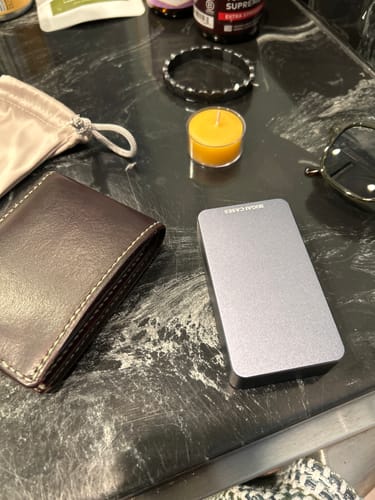Customer's silver Mission Case on a black countertop next to a wallet, pouch, and other personal items.