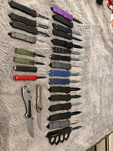 Customer's large collection of OTF knives, including the VT Black Ghost, laid out on a gray surface.