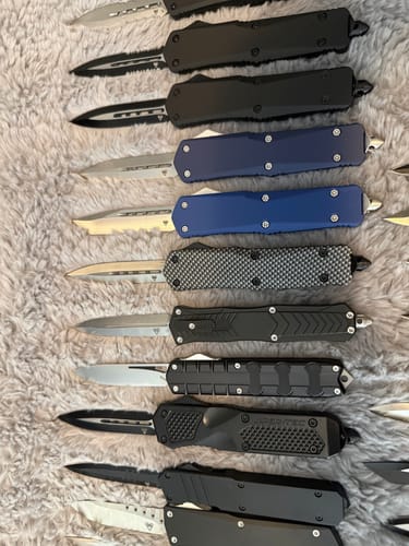 Customer's Blue Ghost OTF Knife shown in a close-up with a collection of other OTF knives on a blanket.