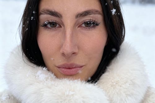 Reviewer's close-up wearing fluffy Fluffy UltraVolume lashes in a snowy outdoor scene.