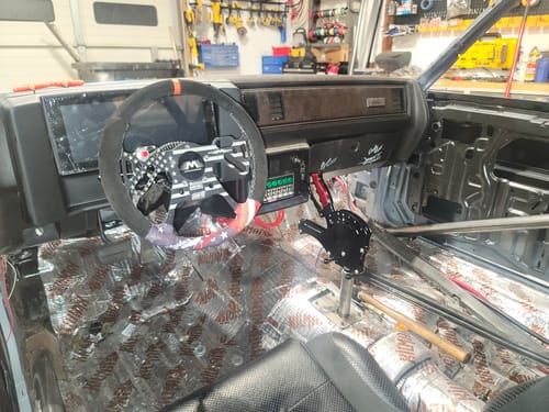 Customer's red Operator Billet Grip Insert Set installed on a black shifter inside a stripped-down car interior.