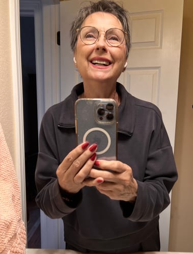 Customer taking a mirror selfie, smiling happily to show off their new Pop On Veneers.