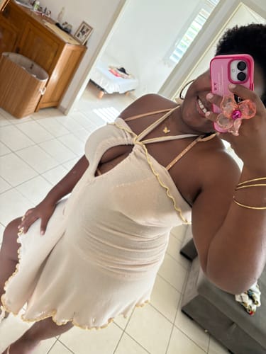 Cliente sonriendo mientras luce la prenda "She Shell" como un vestido corto color champán estilo halter.