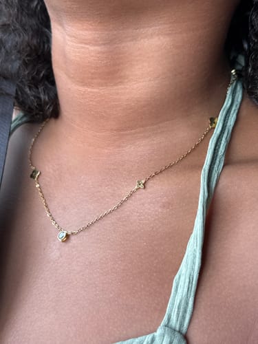 Reviewer wearing the delicate Clover Cutie Chain necklace around their neck.