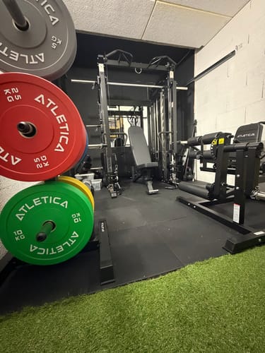 Kunde zeigt die verlegten SolidProtect Bodenschutzmatten in einem gut ausgestatteten Heim-Fitnessstudio.