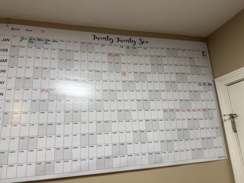 Reviewer's large 2026 Yearly Calendar mounted on a wall, with dates filled in with colorful handwritten notes.