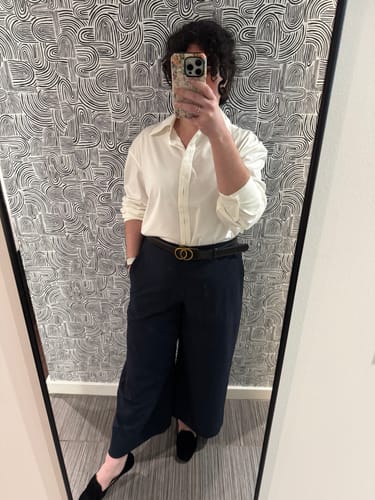 Reviewer wearing the white Filomina Friday Shirt, styled for an oversized look with dark pants and a belt.