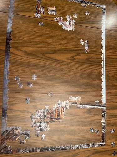Reviewer's partially completed Shuttle in the Orbiter Processing Facility puzzle on a wooden surface, showing the completed border.