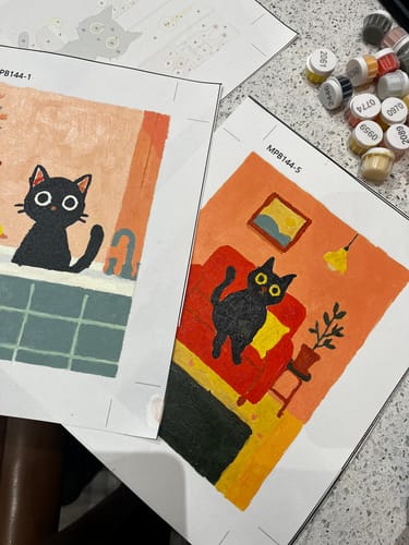 Reviewer's two completed mini paintings from The Black Cat Set showing cats in a tub and on a red chair.